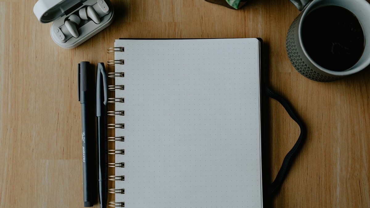 木の机に置いたノートとコーヒーを前に投資の選択肢を整理するイメージ